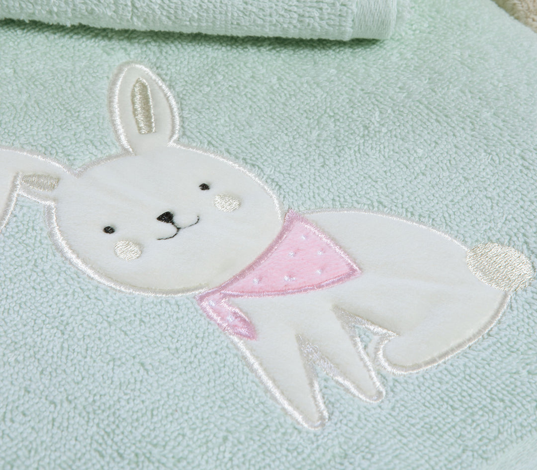 Κοντινό σε βρεφική πετσέτα με κεντημένο σχέδιο λαγουδάκι και ροζ μαντήλι σε απαλό πράσινο ύφασμα.