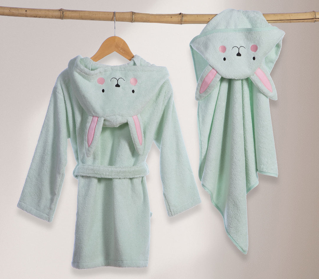 Βρεφικό μπουρνούζι με κουκούλα λαγουδάκι κρεμασμένο σε κρεμάστρα δίπλα σε βρεφική κάπα στο ίδιο σχέδιο.