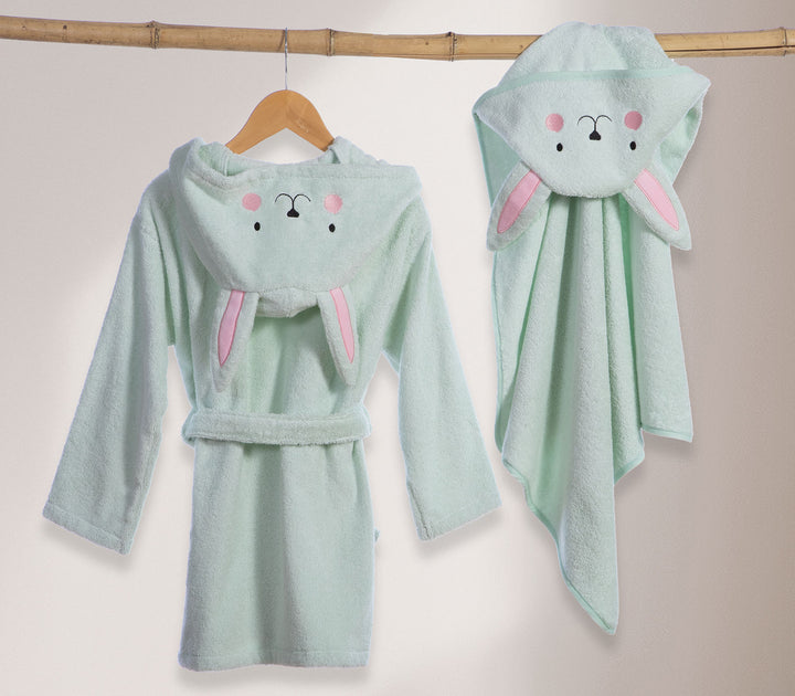 Βρεφικό μπουρνούζι με κουκούλα λαγουδάκι κρεμασμένο σε κρεμάστρα δίπλα σε βρεφική κάπα στο ίδιο σχέδιο.