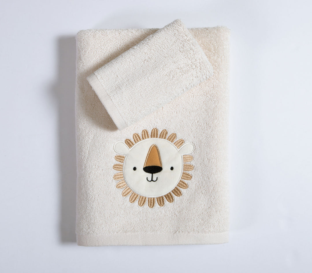 Εκρού βρεφική πετσέτα με κεντημένο σχέδιο λιονταριού και μικρή πετσέτα τοποθετημένη επάνω σε καθαρό λευκό φόντο στούντιο.