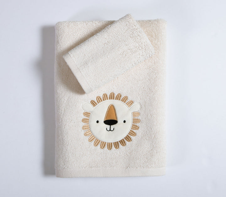 Εκρού βρεφική πετσέτα με κεντημένο σχέδιο λιονταριού και μικρή πετσέτα τοποθετημένη επάνω σε καθαρό λευκό φόντο στούντιο.