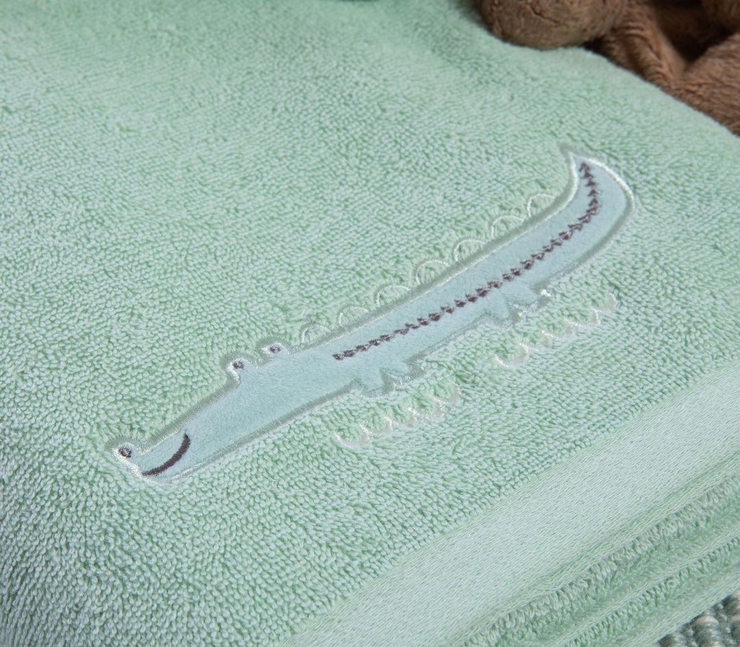 Κοντινό σε πράσινη βρεφική πετσέτα με κεντημένο σχέδιο κροκόδειλου πάνω σε απαλή βαμβακερή πετσέτα.