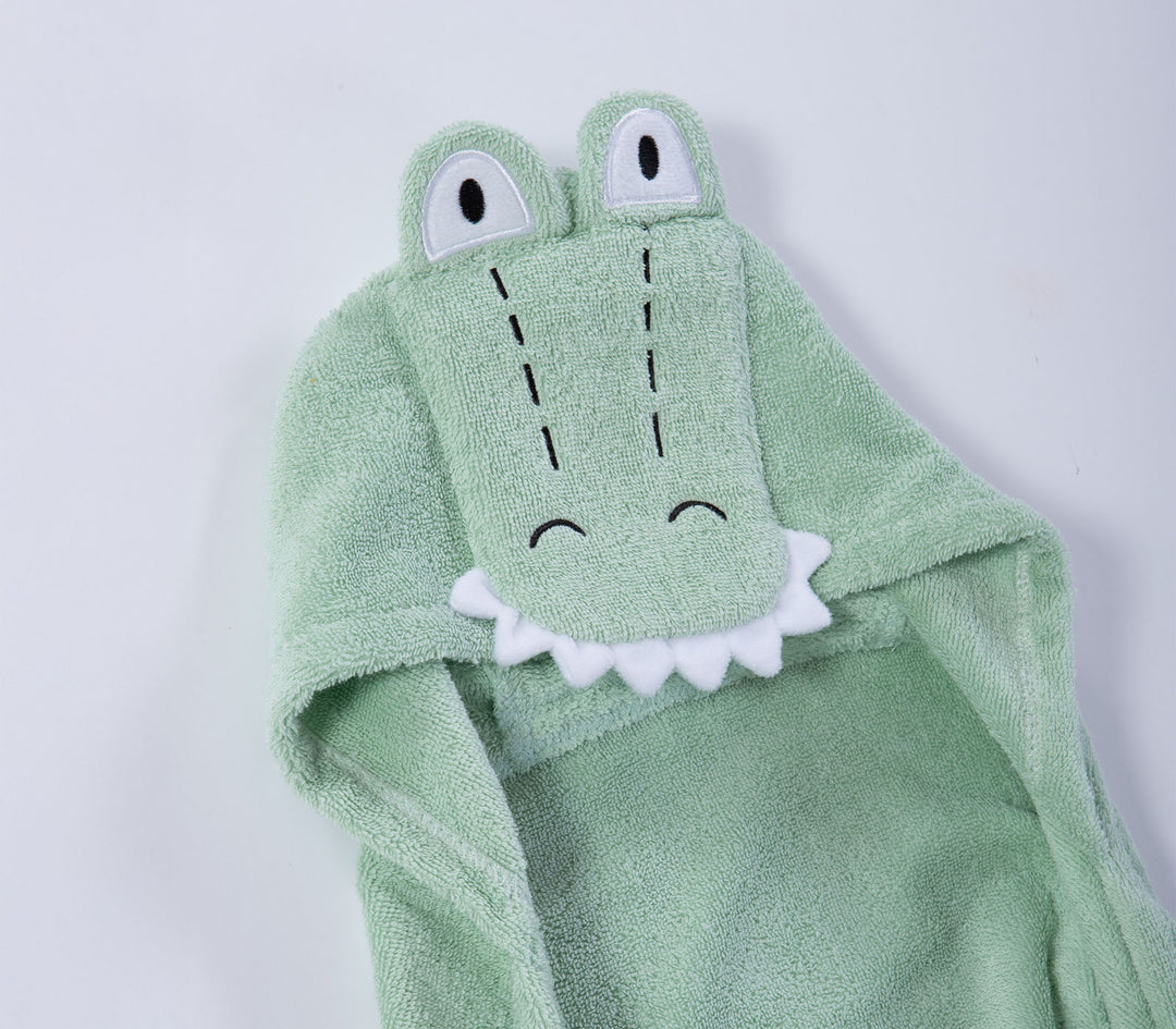 Κοντινό σε κουκούλα βρεφικής κάπας πράσινης με χαριτωμένο σχέδιο κροκόδειλου και μικρές υφασμάτινες λεπτομέρειες.