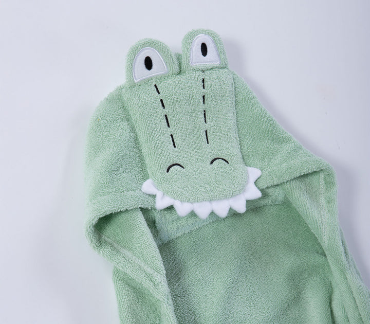 Κοντινό σε κουκούλα βρεφικής κάπας πράσινης με χαριτωμένο σχέδιο κροκόδειλου και μικρές υφασμάτινες λεπτομέρειες.