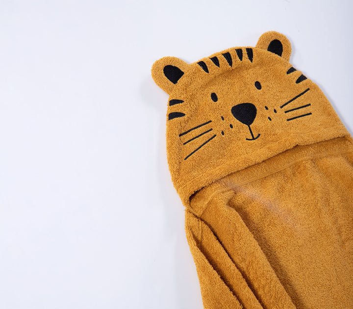 Κοντινή λήψη σε χρυσή βρεφική κάπα μπάνιου με κουκούλα και σχέδιο τίγρης σε λευκό φόντο.
