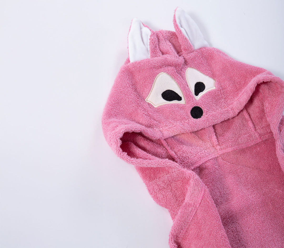 Κοντινή λήψη σε ροζ βρεφική κάπα μπάνιου με κουκούλα και σχέδιο αλεπούς σε λευκό φόντο.