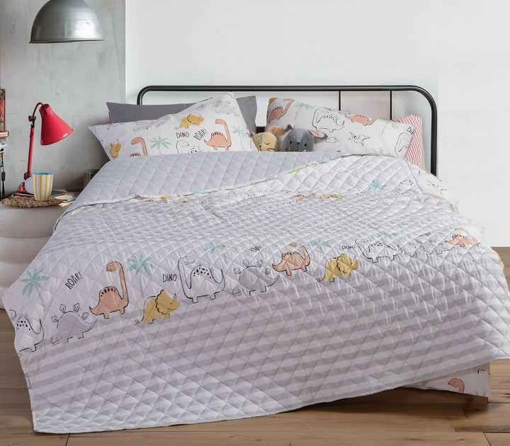 Παιδικό κουβερλί Dinosaur Art της Nef-Nef Homeware σε εκρού και γκρι χρώμα με σχέδια δεινόσαυρων στρωμένο σε παιδικό κρεβάτι.