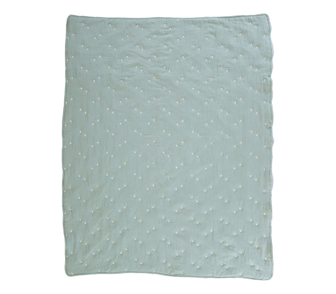 Μέντα βρεφικό κουβερλί απλωμένο σε λευκό φόντο με διάσπαρτα μικρά κεντημένα αστέρια.