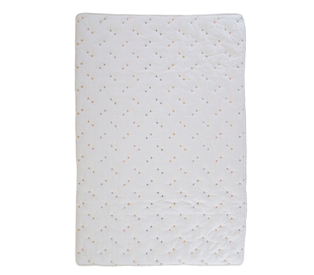 Βρεφικό κουβερλί σε εκρού απόχρωση με μικρά παστέλ αστέρια απλωμένο σε λευκό φόντο φωτογράφισης.
