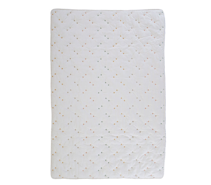 Βρεφικό κουβερλί σε εκρού απόχρωση με μικρά παστέλ αστέρια απλωμένο σε λευκό φόντο φωτογράφισης.