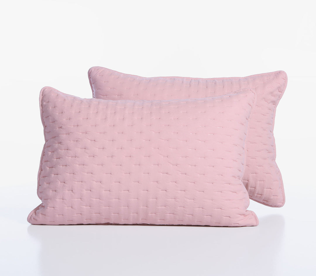 Δύο ροζ διακοσμητικές μαξιλαροθήκες με διακριτικό καπιτονέ σχέδιο τοποθετημένες η μία μπροστά από την άλλη.