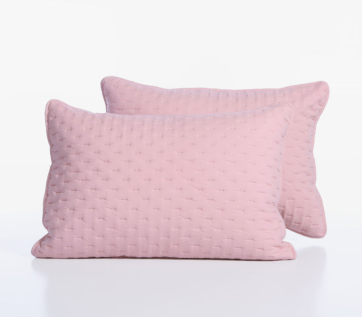 Δύο ροζ διακοσμητικές μαξιλαροθήκες με διακριτικό καπιτονέ σχέδιο τοποθετημένες η μία μπροστά από την άλλη.