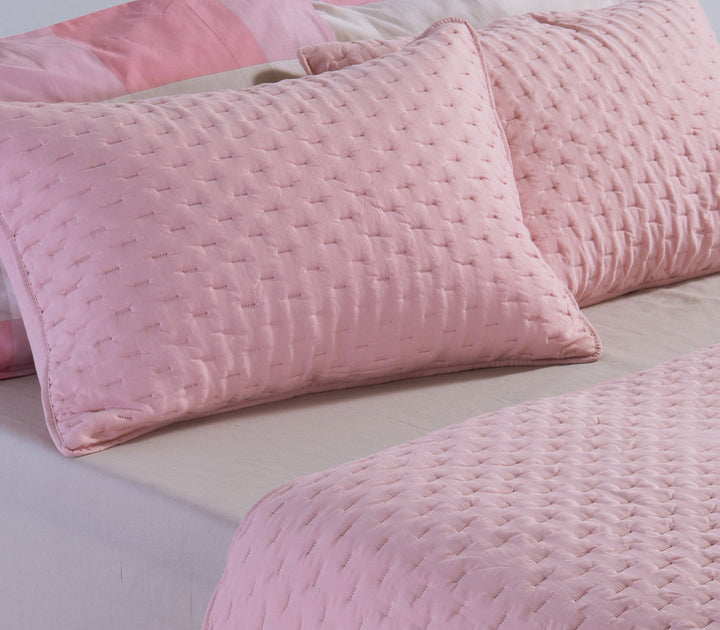 Ροζ διακοσμητικές μαξιλαροθήκες τοποθετημένες σε κρεβάτι με καπιτονέ υφή και απαλή υφασμάτινη επιφάνεια.