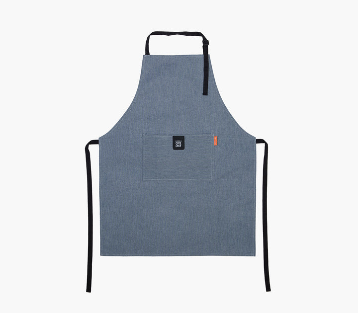 Μπλε ποδιά κουζίνας με μαύρα λουράκια και πρακτική μπροστινή τσέπη σε ουδέτερο φόντο.