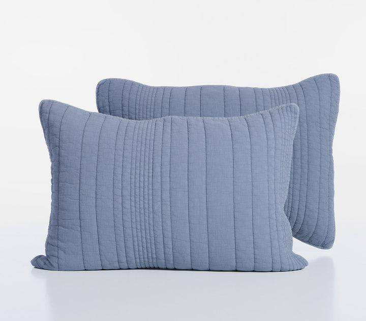 Δύο βαμβακερές μαξιλαροθήκες σε μπλε απόχρωση με καπιτονέ υφή και διακριτικές ραφές τοποθετημένες σε λευκό φόντο.