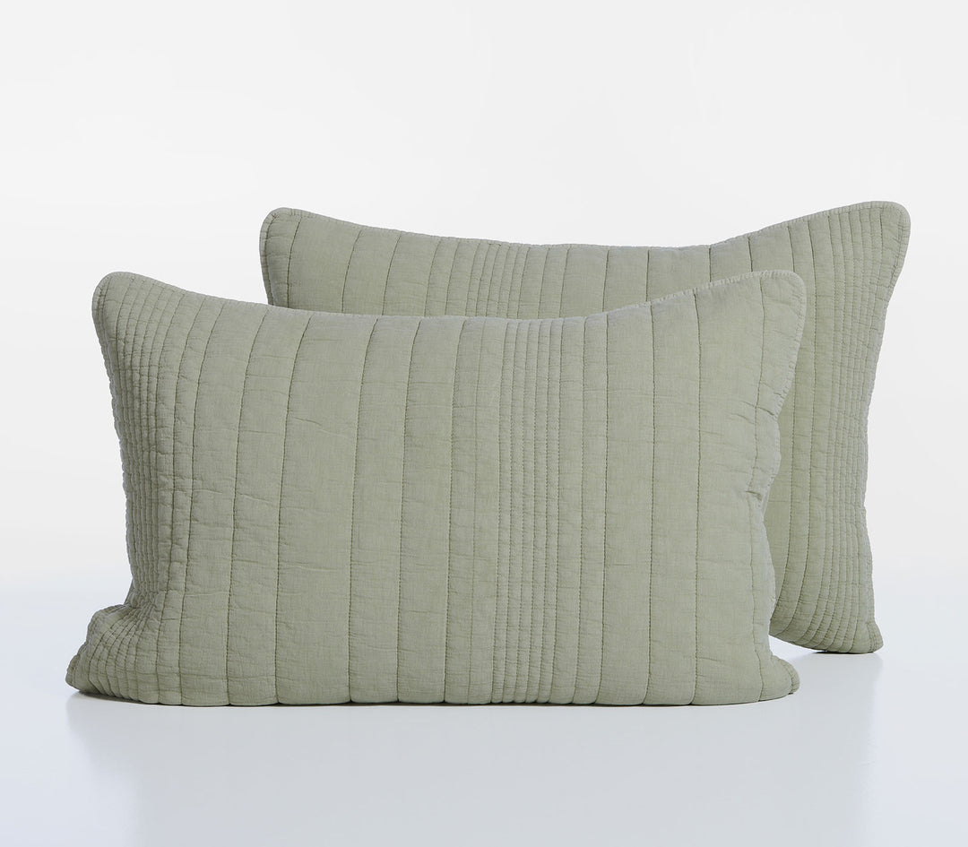Δύο διακοσμητικές μαξιλαροθήκες σε απαλό πράσινο χρώμα με καπιτονέ κάθετες ραφές τοποθετημένες σε λευκό φόντο στούντιο.