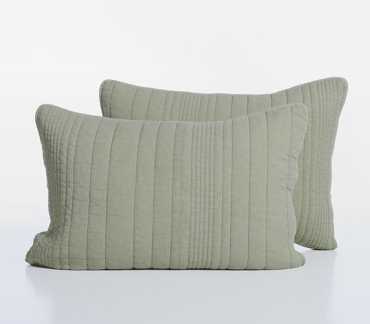 Δύο διακοσμητικές μαξιλαροθήκες σε απαλό πράσινο χρώμα με καπιτονέ κάθετες ραφές τοποθετημένες σε λευκό φόντο στούντιο.