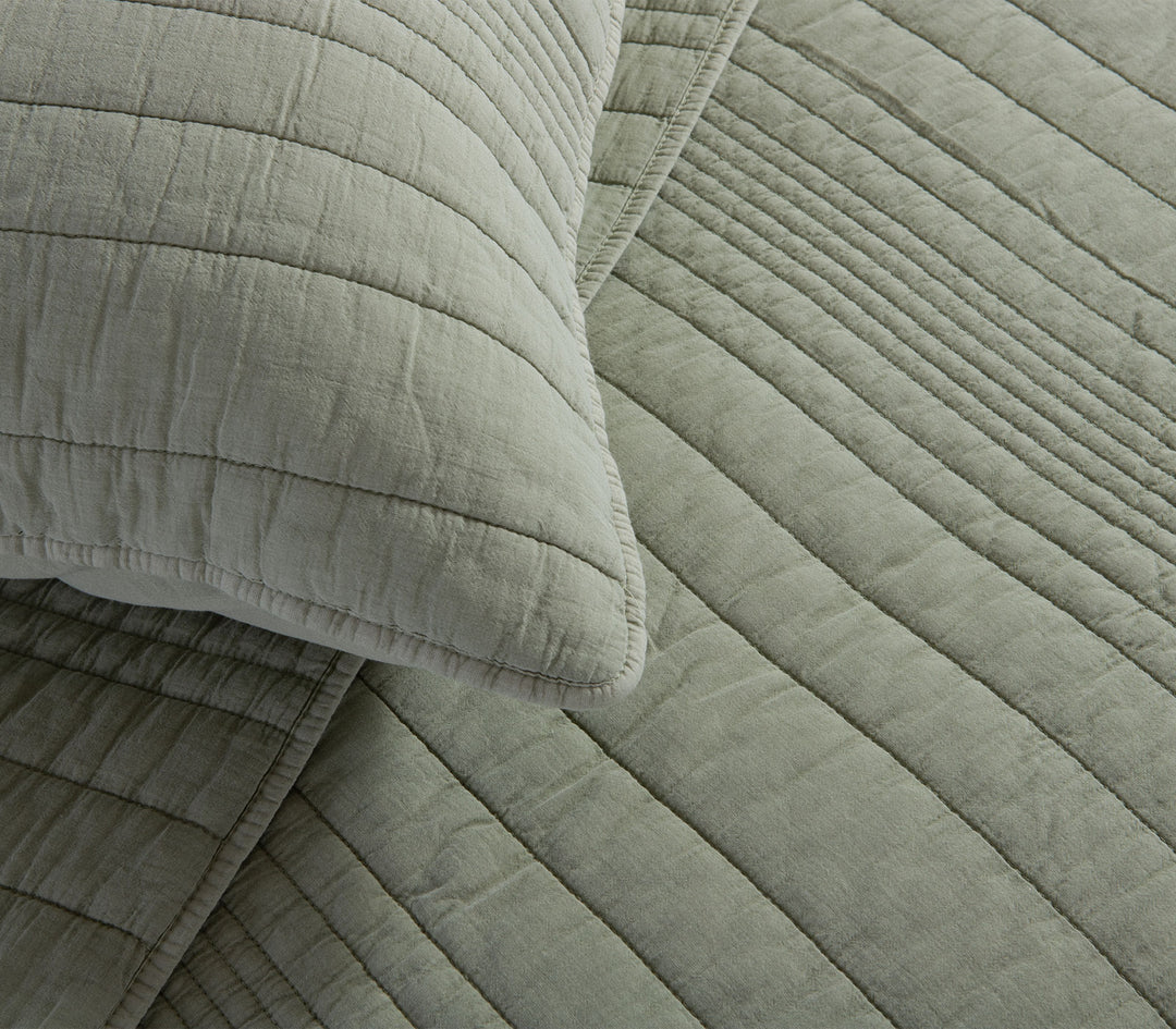 Κοντινό πλάνο πράσινης καπιτονέ μαξιλαροθήκης που αναδεικνύει την υφή του υφάσματος και τις διακριτικές ραφές.