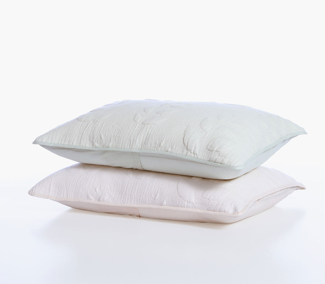 Δύο διακοσμητικές μαξιλαροθήκες σε εκρού και απαλό πράσινο χρώμα με ανάγλυφο φυλλωτό σχέδιο.