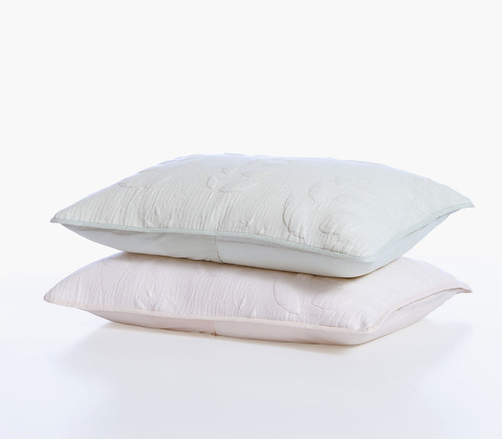 Δύο διακοσμητικές μαξιλαροθήκες σε εκρού και απαλό πράσινο χρώμα με ανάγλυφο φυλλωτό σχέδιο.