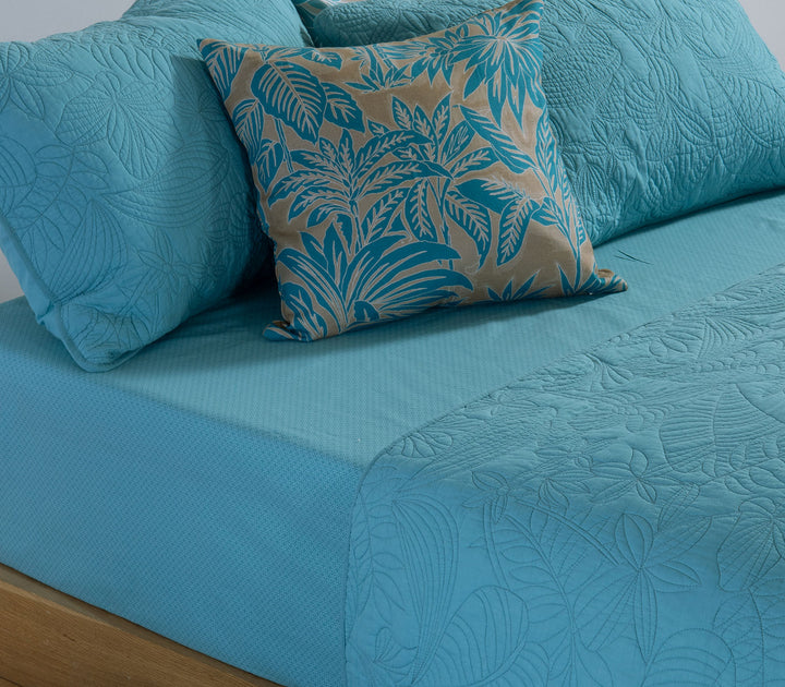 Κρεβάτι με μπλε καπιτονέ κουβερλί Nef-Nef Homeware και μαξιλάρια στο ίδιο ύφος πάνω σε απαλό πράσινο σεντόνι.