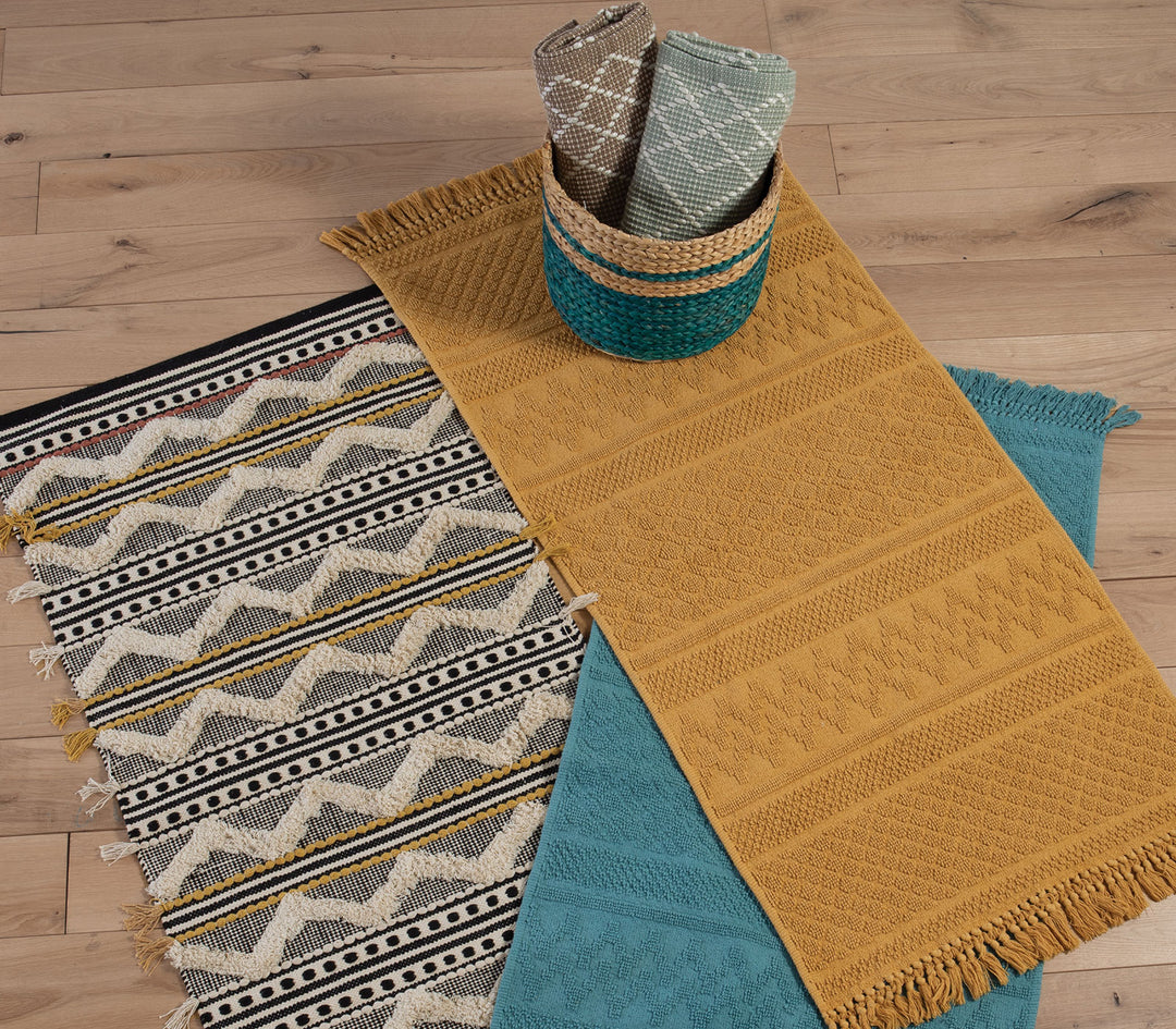 Χαλάκια κουζίνας σε μουσταρδί, τιρκουάζ και μπεζ αποχρώσεις τοποθετημένα σε ξύλινο δάπεδο με διακοσμητικό καλάθι.