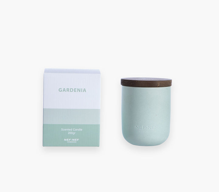 Αρωματικό χώρου με στικς Gardenia της Nef-Nef Homeware πάνω σε τραπέζι σαλονιού μπροστά από καναπέ με διακοσμητικά μαξιλάρια.