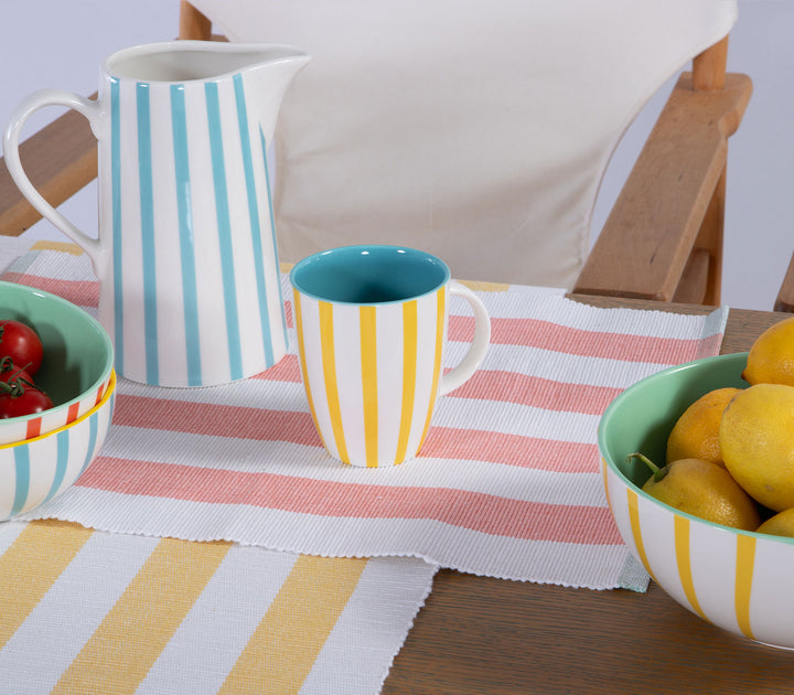 Κεραμική ριγέ κανάτα σε τραπέζι με σερβίτσιο σε παστέλ αποχρώσεις και καλοκαιρινό ύφος.