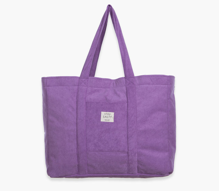 Μωβ τσάντα θαλάσσης μονόχρωμη με υφασμάτινες λαβές και εξωτερική τσέπη σε λευκό φόντο.