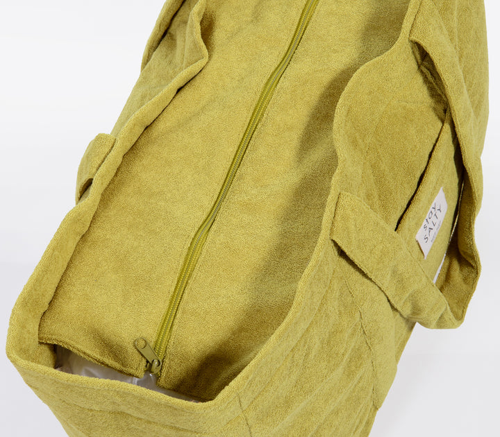 Κοντινό σε λαχανί τσάντα θαλάσσης με φερμουάρ και μαλακή υφή υφάσματος σε ουδέτερο φόντο.