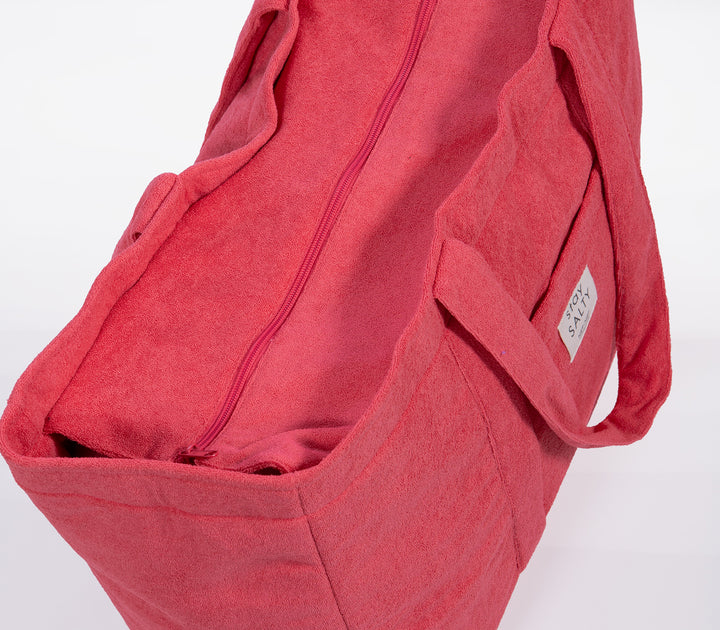 Κοντινό σε κοραλί τσάντα θαλάσσης με φερμουάρ και μαλακή υφή υφάσματος σε ουδέτερο φόντο.