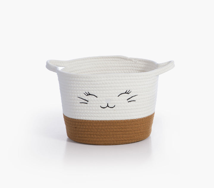 Μπεζ καλάθι αποθήκευσης Hilda της Nef-Nef Homeware από βαμβακερό σχοινί με κεντημένο χαμογελαστό πρόσωπο σε ουδέτερο φόντο.
