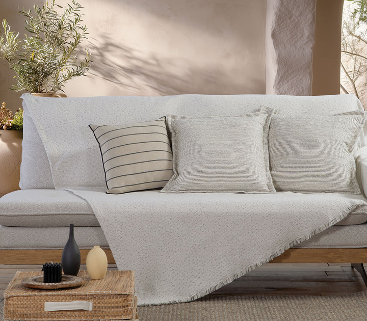 Ριχτάρι Malta 26 της Nef-Nef Homeware σε εκρού με διακριτικές μαύρες πινελιές απλωμένο σε καναπέ σαλονιού με διακοσμητικά μαξιλάρια.