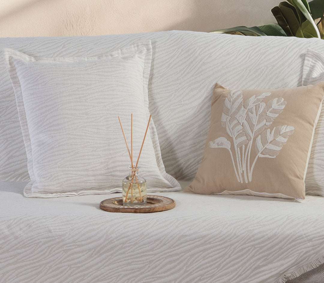 Διακοσμητικά μαξιλάρια Zebra σε εκρού καναπέ με διακοσμητικό αρωματικό χώρου και minimal διακόσμηση.