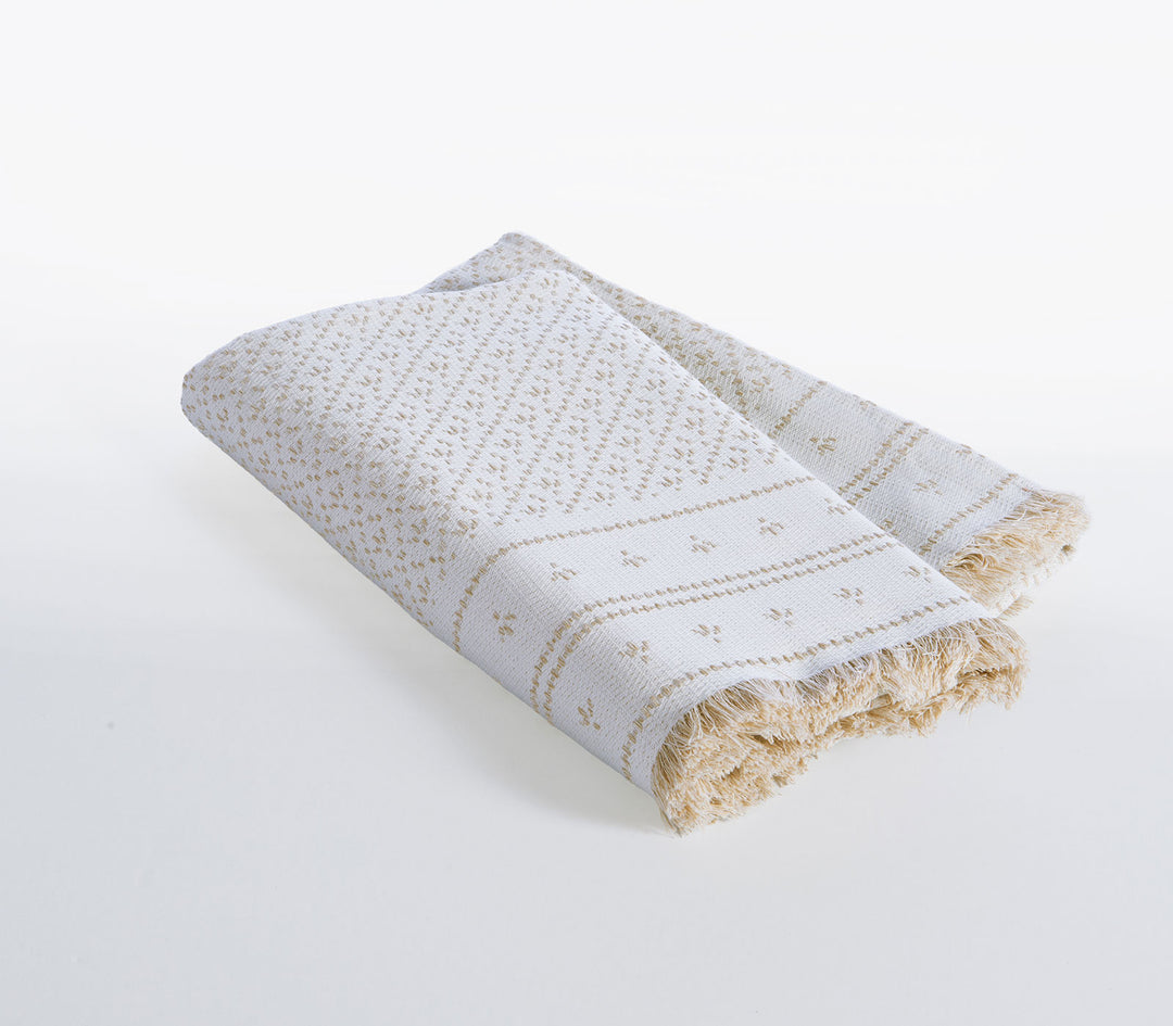 Μπεζ ριχτάρι πολυθρόνας Ishmar της Nef-Nef Homeware διπλωμένο με υφαντό μοτίβο και κρόσσια σε λευκό ουδέτερο φόντο.