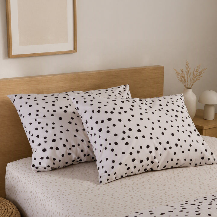 Μαξιλαροθήκες ύπνου Trust Nef-Nef Homeware σε εκρού με καφέ πουά σχέδιο, τοποθετημένες σε κρεβάτι με ξύλινο κεφαλάρι.