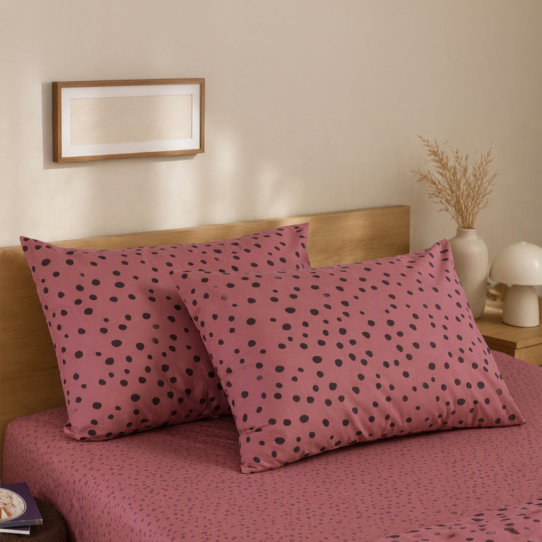 Μαξιλαροθήκες Trust Nef-Nef Homeware σε ροζ απόχρωση με σκούρο πουά μοτίβο, τοποθετημένες σε μοντέρνο υπνοδωμάτιο.