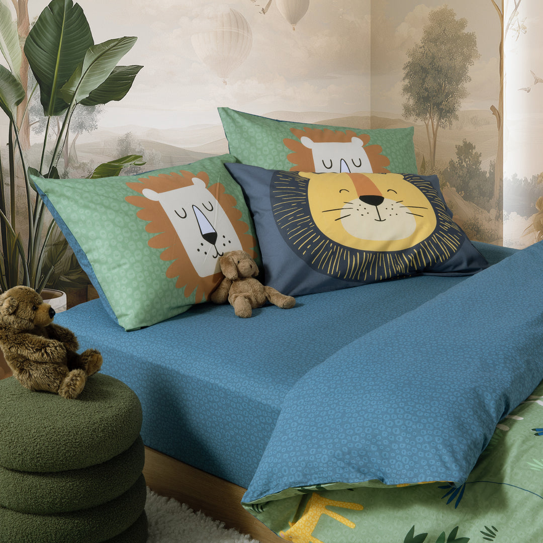 Παιδικό σετ σεντονιών Nef-Nef στρωμένο σε κρεβάτι, με πράσινες μαξιλαροθήκες με λιοντάρια και μπλε σεντόνι με διακριτικό μοτίβο.