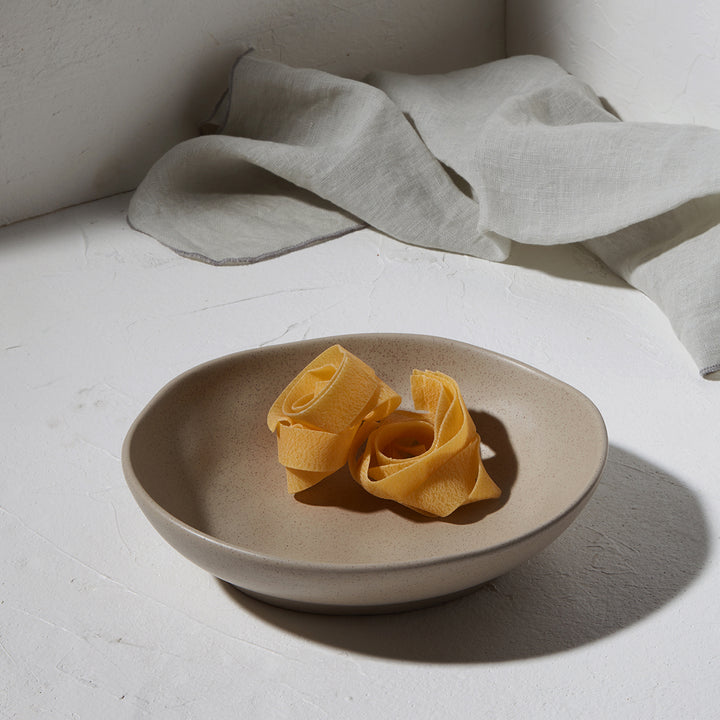 Πιάτο βαθύ Mare της Estia σε φυσικό φόντο με υφασμάτινη πετσέτα και φωτισμό από το πλάι, με ζυμαρικά στο εσωτερικό του.