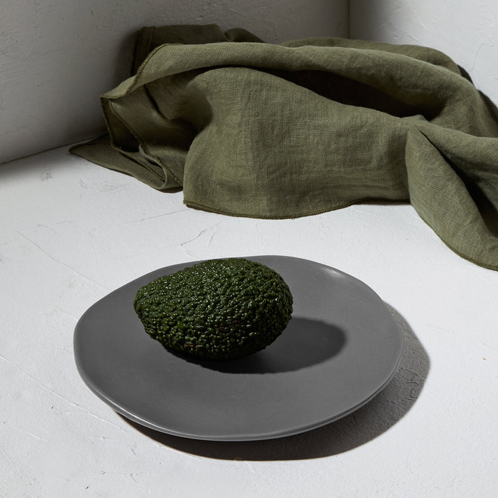 Πιάτο σε σκηνικό με λινό ύφασμα και ένα αβοκάντο στο κέντρο, σε φυσικό φωτισμό.