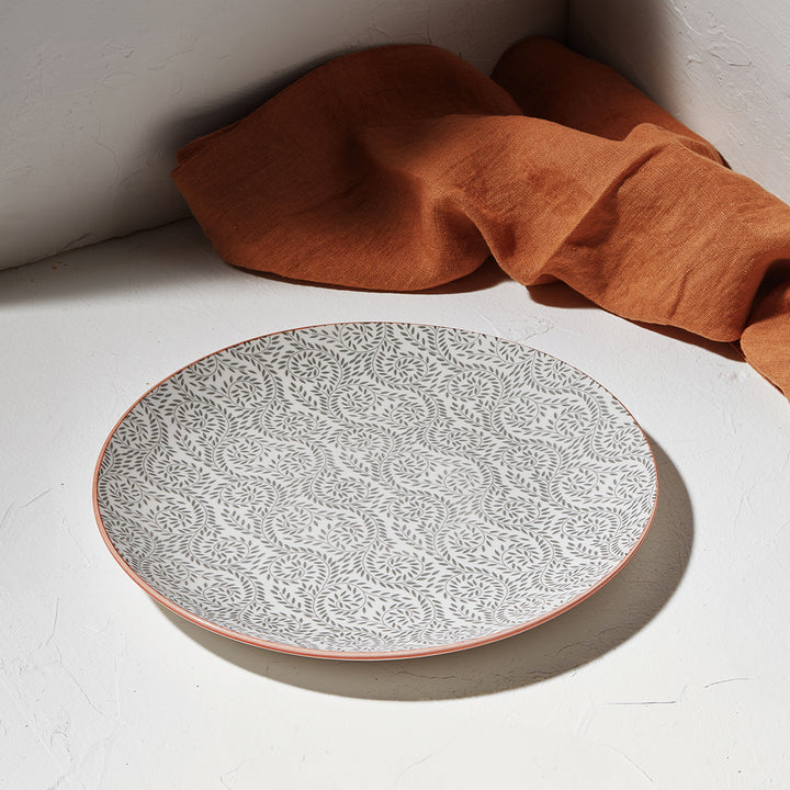 Ρηχό πιάτο Estia τοποθετημένο σε λευκή επιφάνεια με πορτοκαλί πανί στο φόντο.