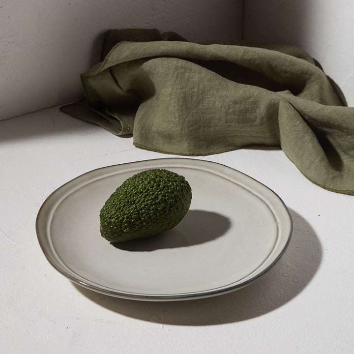 Πιάτο Deline γκρι απόχρωσης με αβοκάντο σε λευκή επιφάνεια και πράσινο ύφασμα στο φόντο.