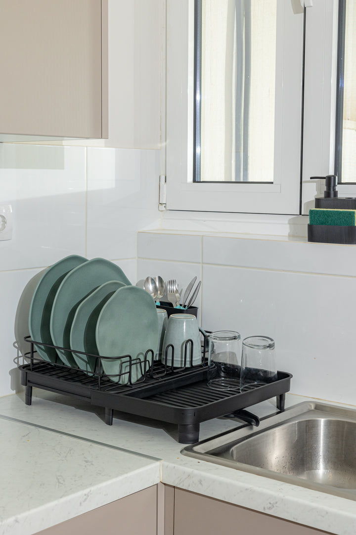 Φωτογραφία lifestyle σε κουζίνα που δείχνει την πιατοθήκη Estia τοποθετημένη δίπλα στον νεροχύτη, οργανωμένη με πιάτα και ποτήρια, αναδεικνύοντας τη λειτουργία αποστράγγισης των νερών.