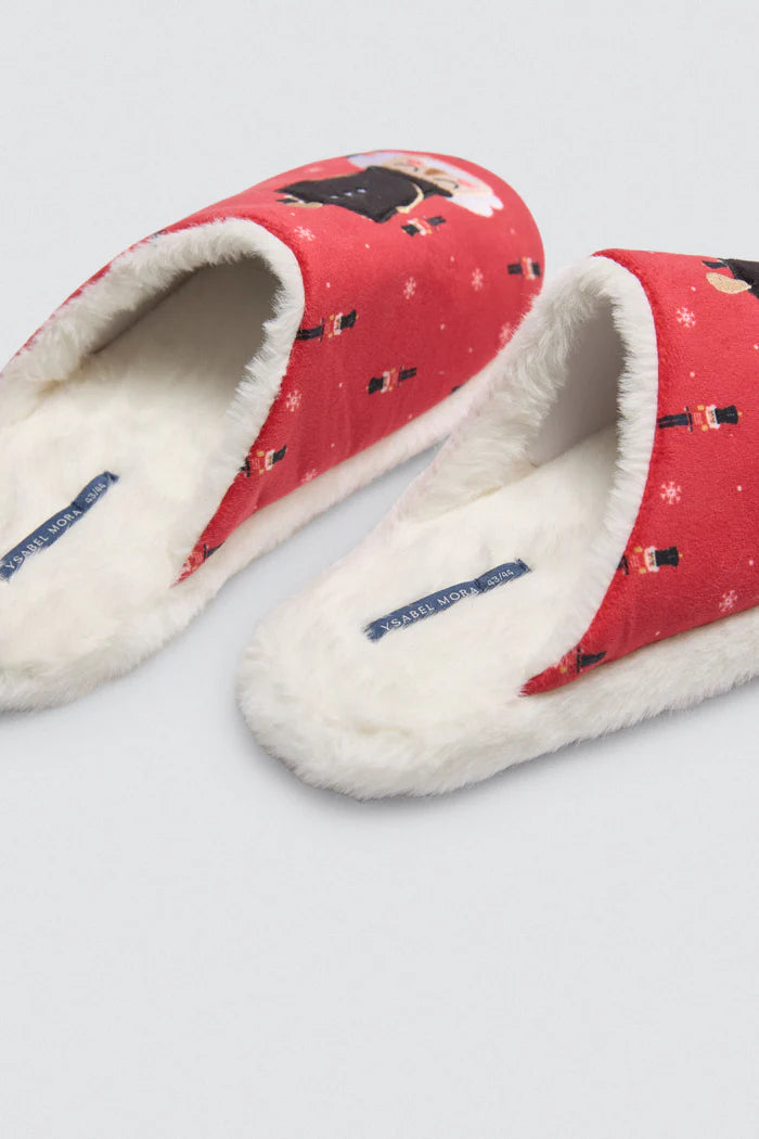 Κοντινή λήψη κόκκινης παντόφλας με σχέδιο καρυοθραύστη και λευκή επένδυση, με φόντο τη σόλα που γράφει “XMAS