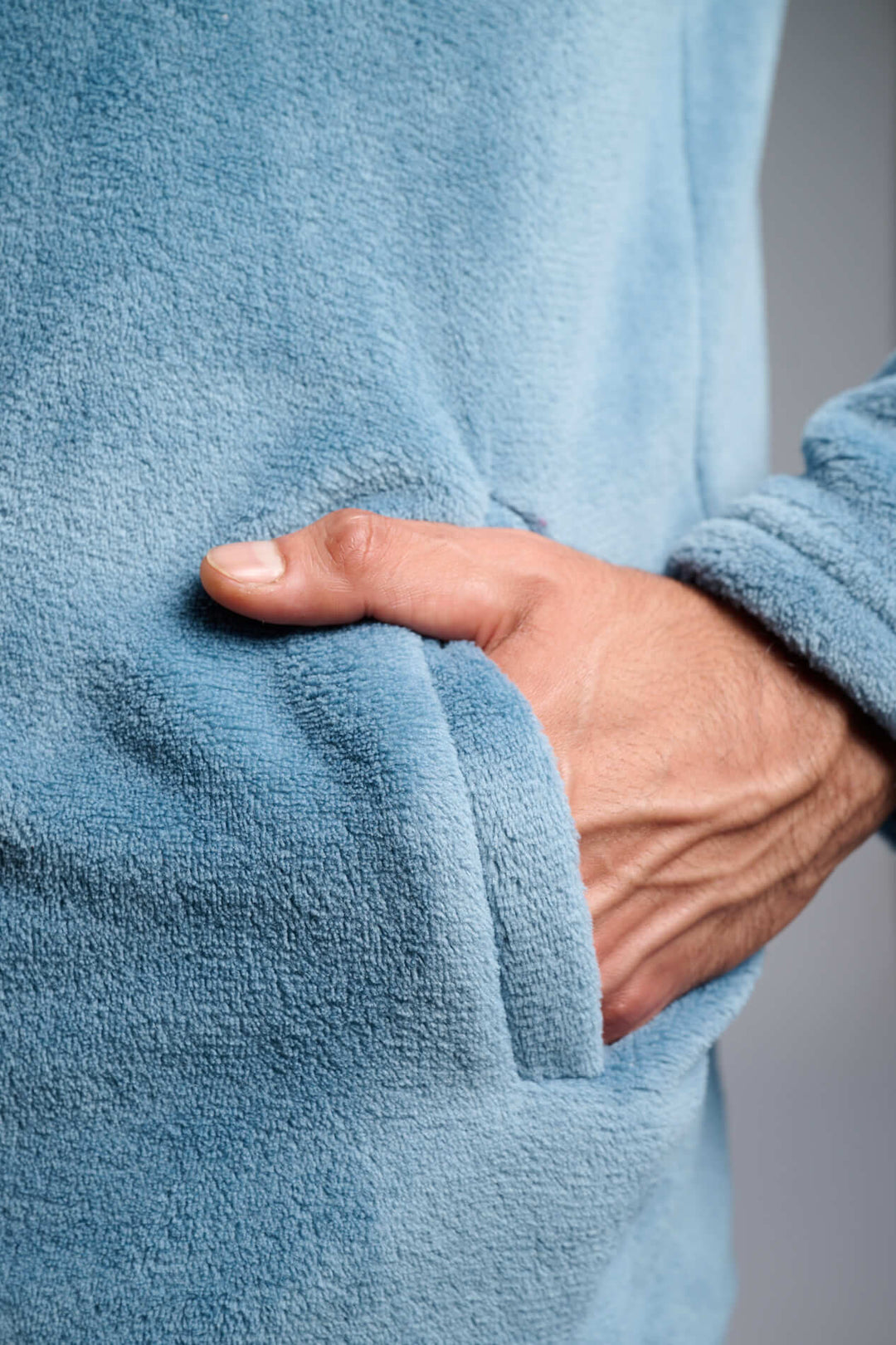 Κοντινή λήψη γαλάζιας fleece ζακέτας με απαλή υφή, με το χέρι στην πλαϊνή τσέπη.