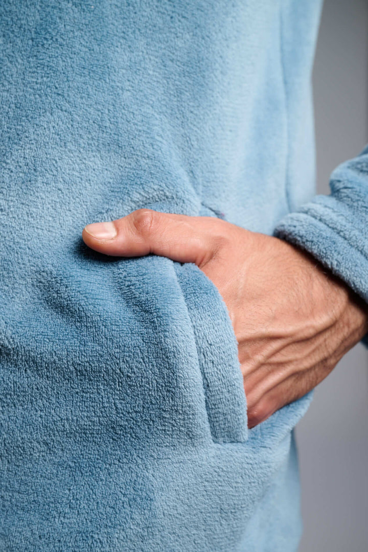 Κοντινή λήψη γαλάζιας fleece ζακέτας με απαλή υφή, με το χέρι στην πλαϊνή τσέπη.