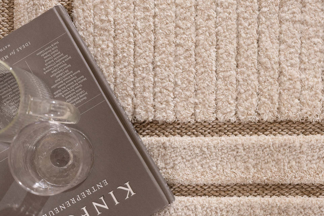 Λεπτομέρεια υφής μπεζ χαλιού με ανάγλυφες ρίγες και καφέ γραμμές στο σχέδιο.