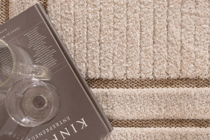 Λεπτομέρεια υφής μπεζ χαλιού με ανάγλυφες ρίγες και καφέ γραμμές στο σχέδιο.