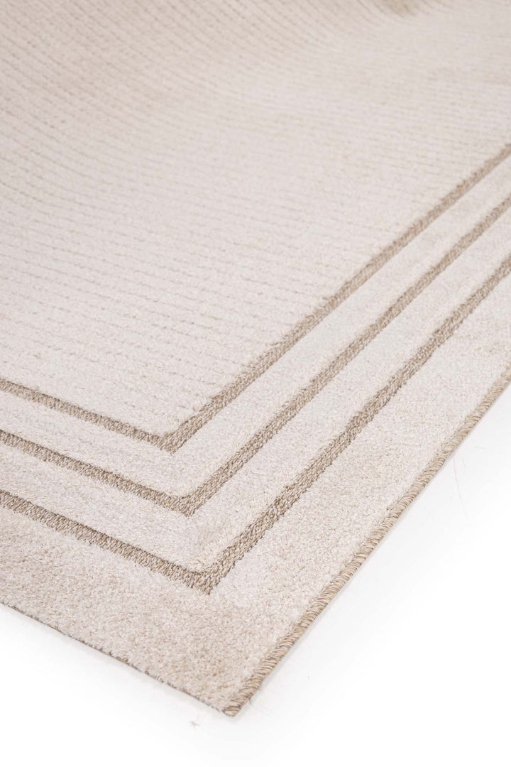 Μπεζ χαλί με τριπλό καφέ πλαίσιο, φωτογραφημένο υπό γωνία για να αναδειχθεί η υφή του.