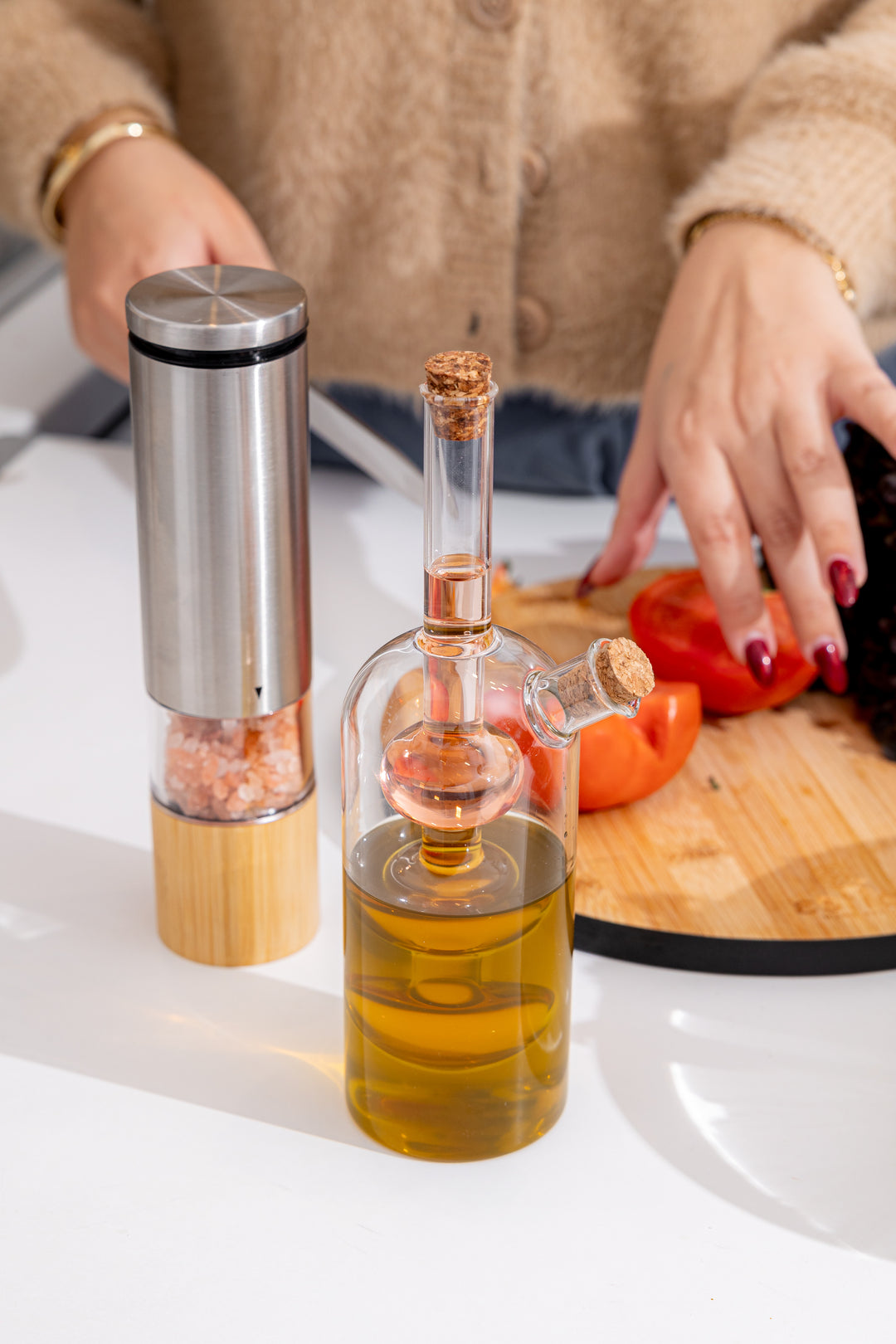 Γυάλινη φιάλη λαδιού με εσωτερικό δοχείο, γεμάτη ελαιόλαδο, τοποθετημένη σε πάγκο κουζίνας με υλικά μαγειρικής.
